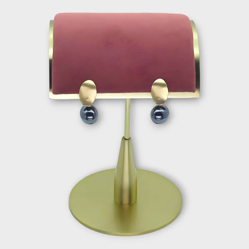 A pair of Auralis Drop earrings with gold oval studs and dark spherical drops on a gold display stand.