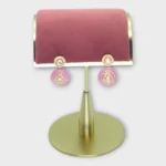 MEENA drop pearl earrings with pink accents displayed on a gold stand, elegant and stylish jewelry piece.