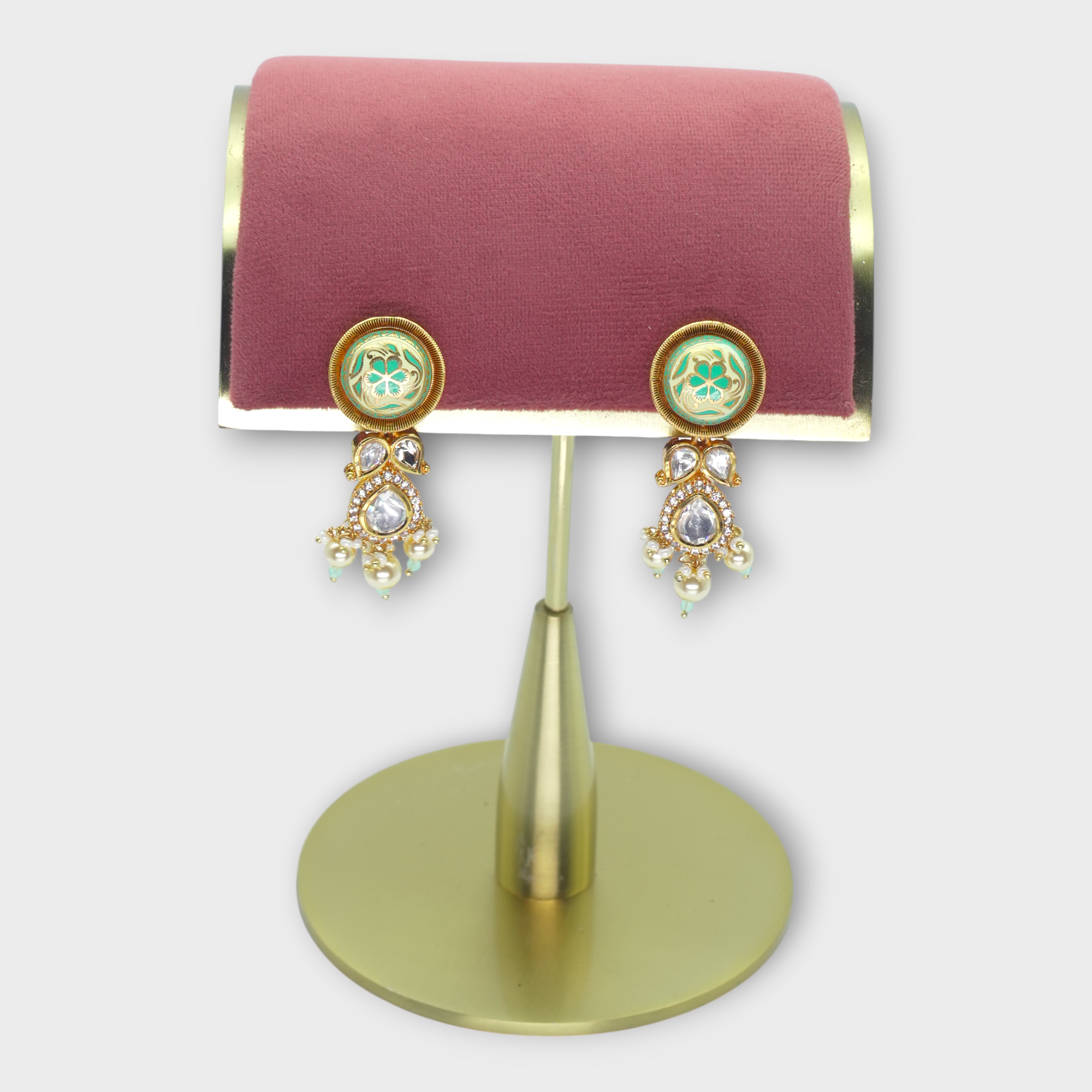 DSC01096 Elegant pearl earrings for bride with green accents and gold detailing displayed on a pink and gold stand.