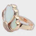 Angle view of STONIRA adjustable rose gold statement ring featuring a carved Mother of Pearl flower motif anchored by a micro-crystal pave cluster