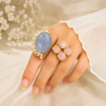 STONIRA adjustable statement ring featuring a large Blue Chalcedony gemstone, Rose Quartz accents, pearl detailing, and a gold-tone setting worn on hand.