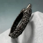 Detailed side profile of STONIRA antique oxidised silver bangle with raised floral carvings
