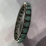 Side view of oxidised silver slip-on bangle inlaid with soft mint green stones in size 2.4
