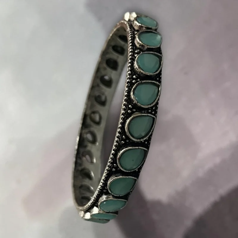Side view of oxidised silver slip-on bangle inlaid with soft mint green stones in size 2.4