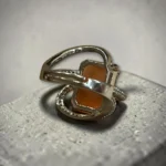 STONIRA adjustable silver cocktail ring featuring the back of rectangular orange cat's eye stone and crystal pavé ribbons