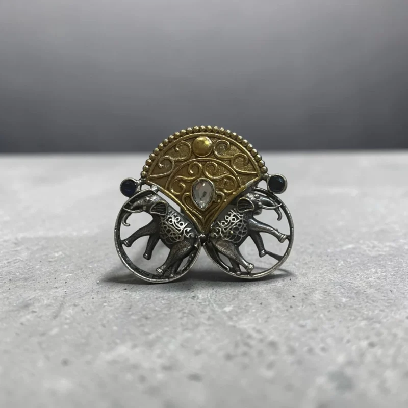 STONIRA adjustable mixed-metal cocktail ring featuring oxidized silver elephants, a golden archway, and sapphire crystal accents