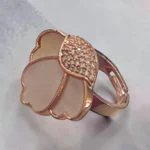 Top view of STONIRA adjustable rose gold statement ring featuring a carved Mother of Pearl flower motif anchored by a micro-crystal pave cluster
