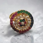 Top view of STONIRA adjustable gold cocktail ring featuring a concentric circular design of multi-colored gemstones and a white pearl halo