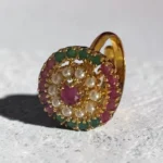 Top of STONIRA high-dome gold cocktail ring featuring a central ruby surrounded by a white pearl halo and alternating rows of rubies and emeralds
