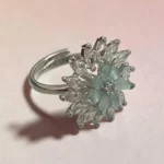 Side view of STONIRA silver cocktail ring featuring a central mint green gemstone flower surrounded by a dramatic starburst halo of clear marquise crystals