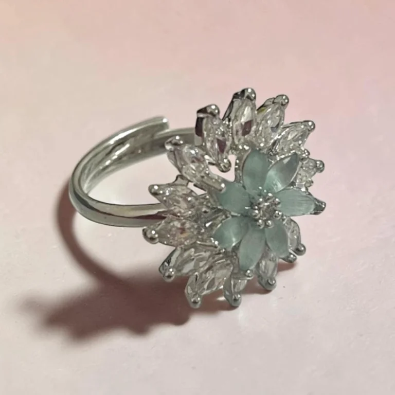 Side view of STONIRA silver cocktail ring featuring a central mint green gemstone flower surrounded by a dramatic starburst halo of clear marquise crystals