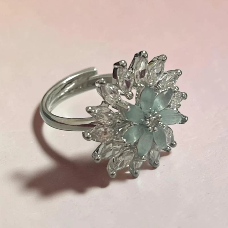 Side view of STONIRA silver cocktail ring featuring a central mint green gemstone flower surrounded by a dramatic starburst halo of clear marquise crystals