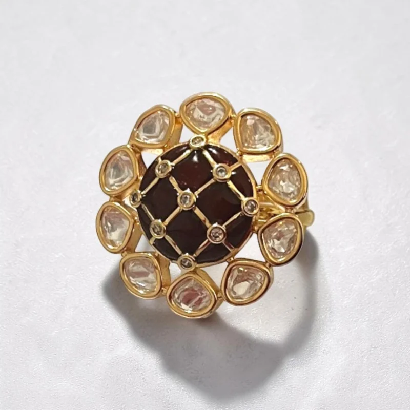 STONIRA gold cocktail ring featuring a central glossy crimson red domed stone with a gold grid overlay and an outer halo of clear teardrop gems