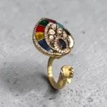 Top view of STONIRA peacock-inspired adjustable statement ring featuring multicolor enamel tail detailing, crystal embellishments, and a gold-tone finish displayed on a neutral background.