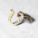 Angle view of STONIRA peacock-inspired adjustable statement ring featuring multicolor enamel tail detailing, crystal embellishments, and a gold-tone finish displayed on a neutral background.