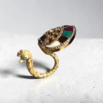 Overview of STONIRA peacock-inspired adjustable statement ring featuring multicolor enamel tail detailing, crystal embellishments, and a gold-tone finish displayed on a neutral background.
