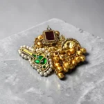 Top view of STONIRA adjustable gold temple charm ring featuring red gemstone, pearl accents, intricate heritage motifs and ghungroo detailing for festive and wedding wear.