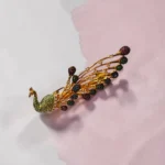 STONIRA peacock-inspired adjustable two-finger statement ring featuring turquoise enamel detailing, multicolour crystal accents, gold-tone finish, and an elegant peacock feather design.