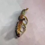 Side view of STONIRA peacock-inspired adjustable two-finger statement ring featuring turquoise enamel detailing, multicolour crystal accents, gold-tone finish, and an elegant peacock feather design.