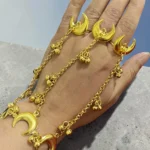 Close up of STONIRA gold crescent moon hathphool ring bracelet draped on hand