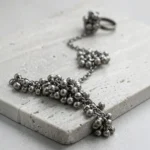 Close up of STONIRA oxidised silver ghungroo haathphool hand harness bracelet featuring bead cluster embellishments and adjustable finger ring