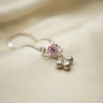 Close-up-of-the-STONIRA-silver-payal-anklet-on-a-fabric-highlighting-the-pink-enamel-charm-and-three-small-hanging-silver-bells.