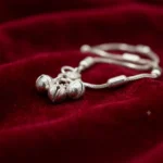 Extreme-macro-shot-focusing-on-the-three-textured-round-silver-bells-and-smooth-cylindrical-slider-charm-of-the-STONIRA-payal-anklet-resting-on-deep-red-velvet-fabric