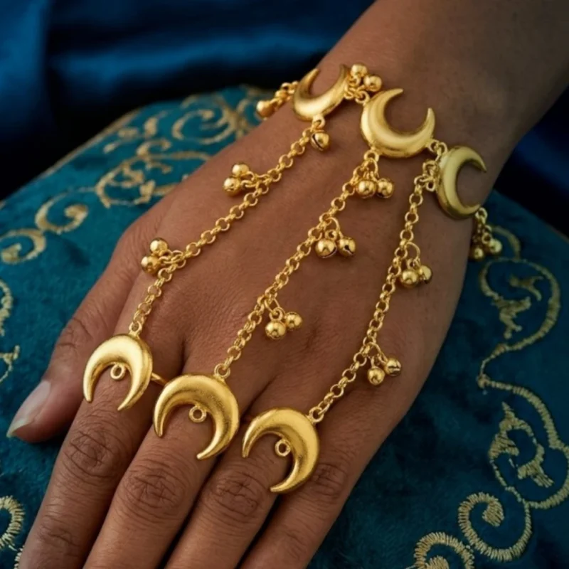 Gold-crescent-moon-hathphool-ring-bracelet-displayed-on-embroidered-cushion-background