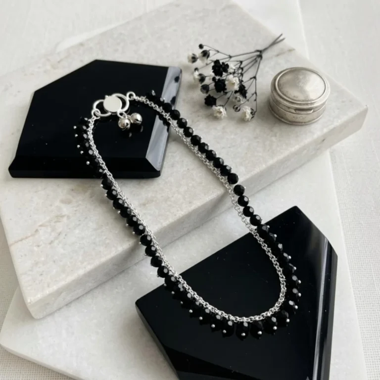 Hand-crafted silver black crystal bead anklet lying flat on stone tray by STONIRA