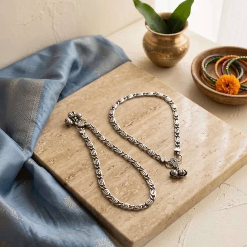 Pair-of-STONIRA-handcrafted-oxidized-silver-S-link-anklets-with-vintage-ghungroo-charms-on-marble-slab.