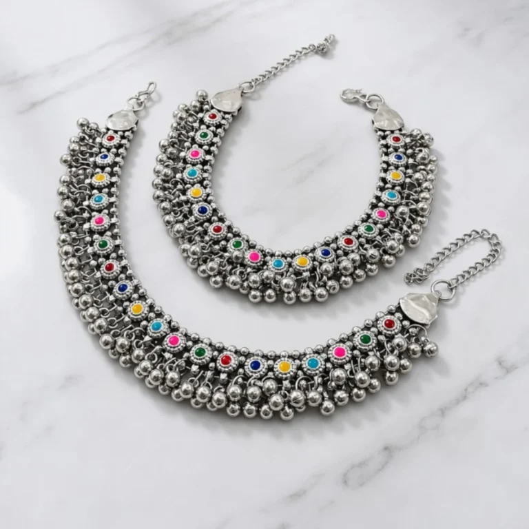 STONIRA-broad-oxidized-silver-payal-set-featuring-colorful-stone-cabochons-and-dense-dangling-ghungroo-bells-on-a-marble-background