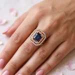 Women-wearing-STONIRA-rose-gold-polished-navy-blue-statement-ring-worn-on-a-hand-highlighting-the-deep-blue-rectangular-gemstone-and-double-crystal-halo