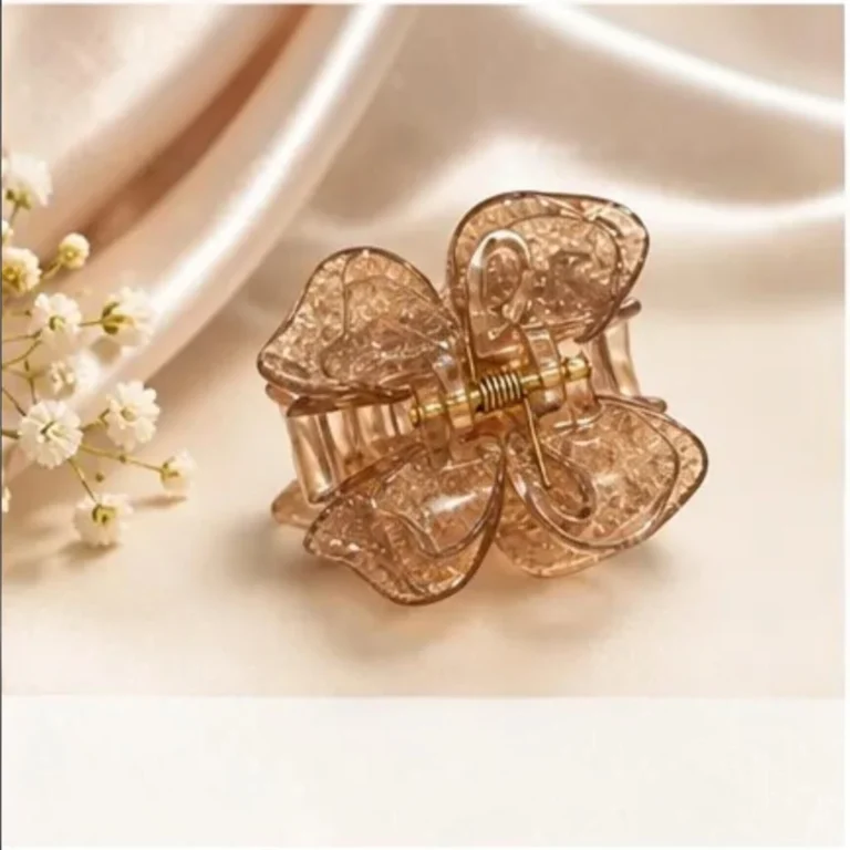 Champagne shimmer resin butterfly hair claw clip with gold-tone spring on marble