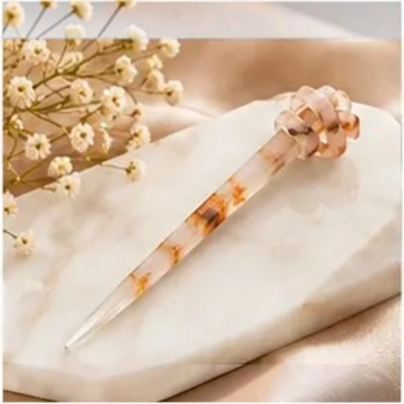 Crystal clear resin hair stick with suspended natural dried botanicals and a sculpted knot detail