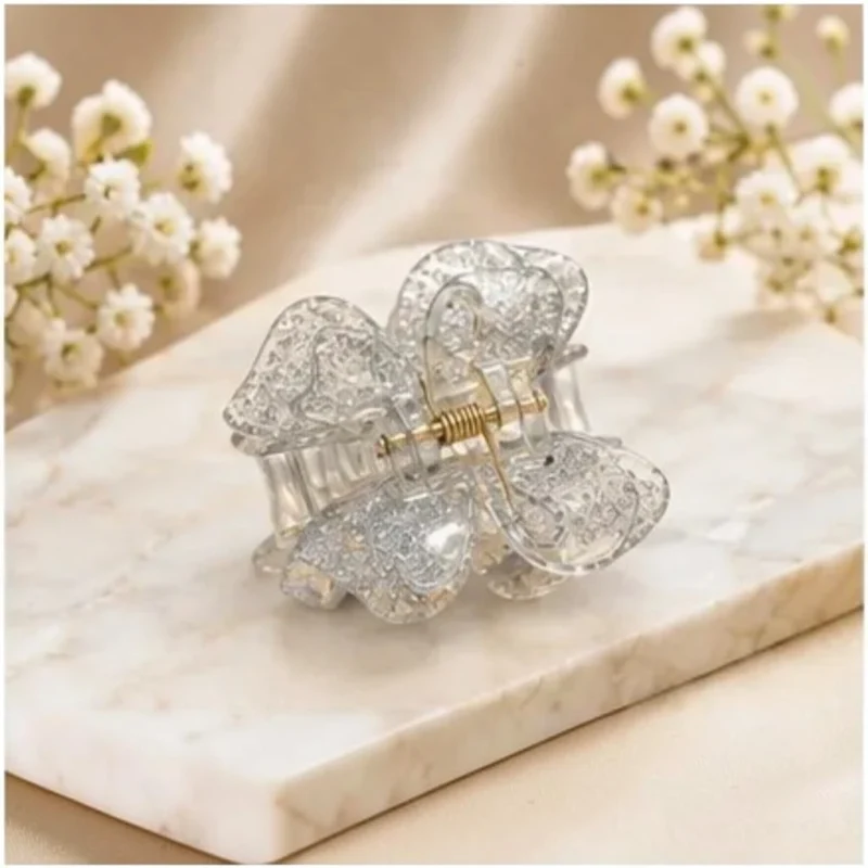 Translucent silver glitter resin butterfly hair claw clip resting on silk.