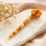 Warm amber mustard resin hair stick with an intricate floral pattern and sculpted knot top