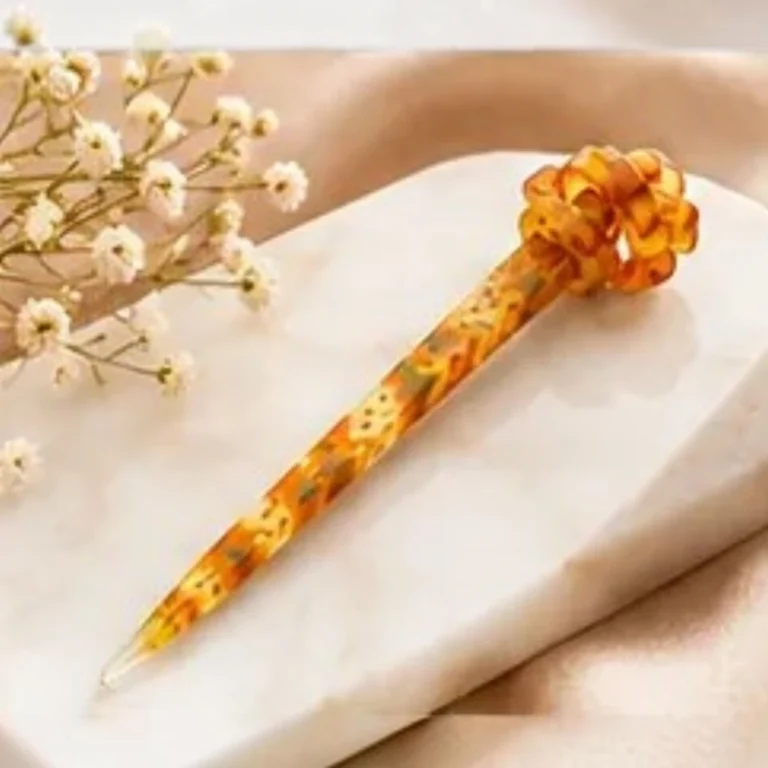 Warm amber mustard resin hair stick with an intricate floral pattern and sculpted knot top